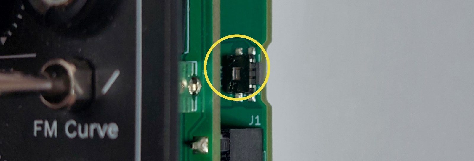 The factory settings button on the bottom circuit board, marked with a yellow circle.